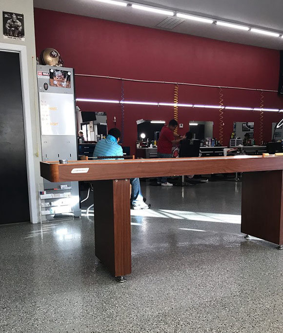 Interior of a barbershop featuring a red wall, a sleek counter, a black door, and colorful decorations hanging above.