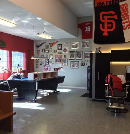 Interior of a sports-themed barbershop featuring a pool table, barber chair, and walls adorned with memorabilia and photos.